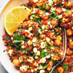 Close up of Mediterranean chickpea casserole topped with parsley, feta and lemon