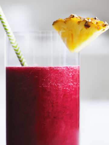 Close up glass of beet pineapple juice with a slice of pineapple