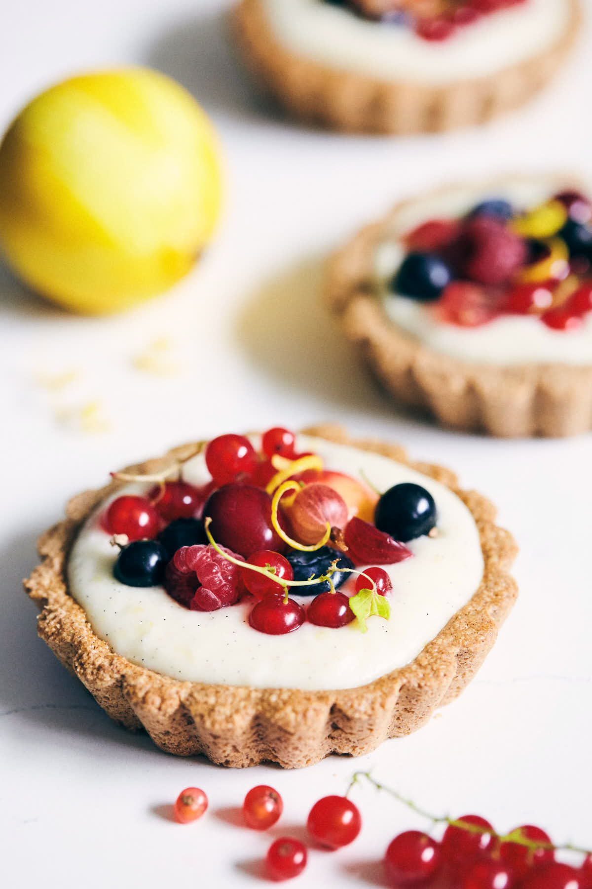 Berry tarts on a marble counter when lemon in background