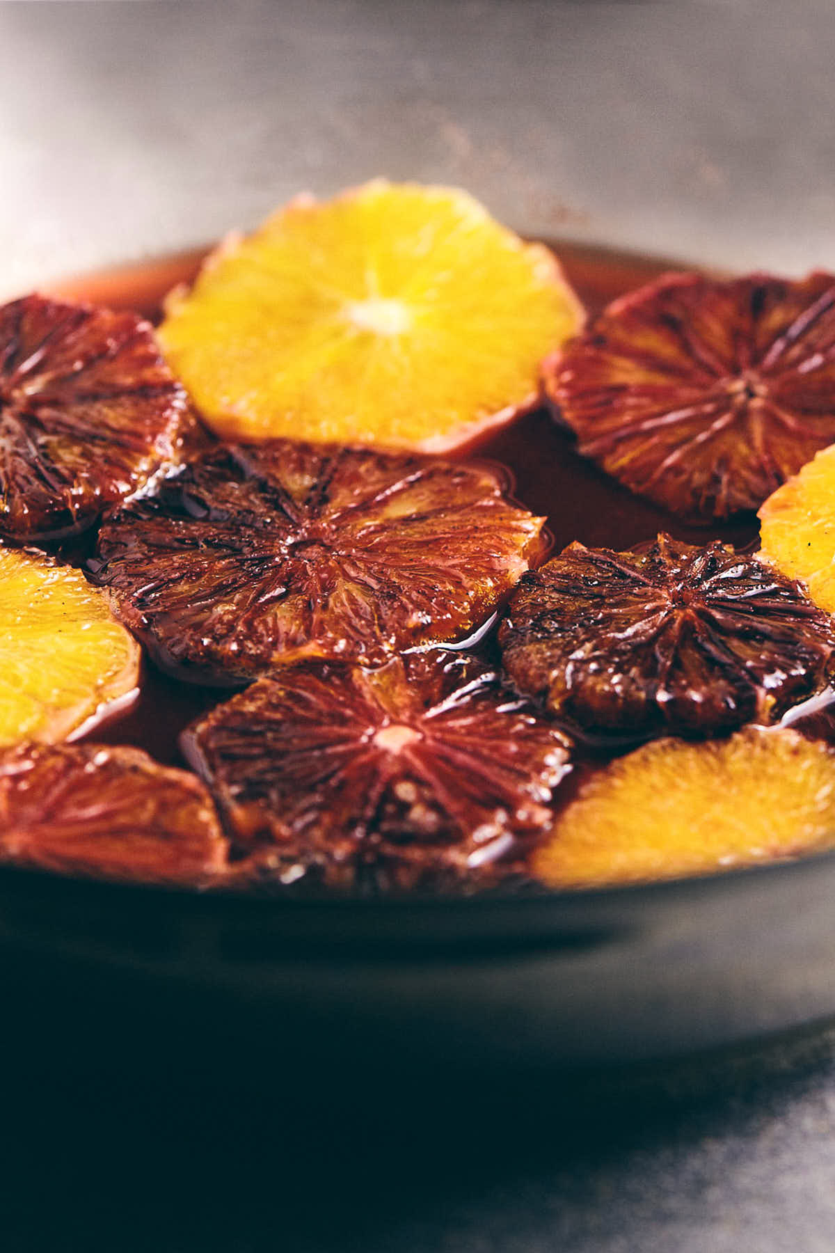 Blood oranges being cooked down in a silver pan
