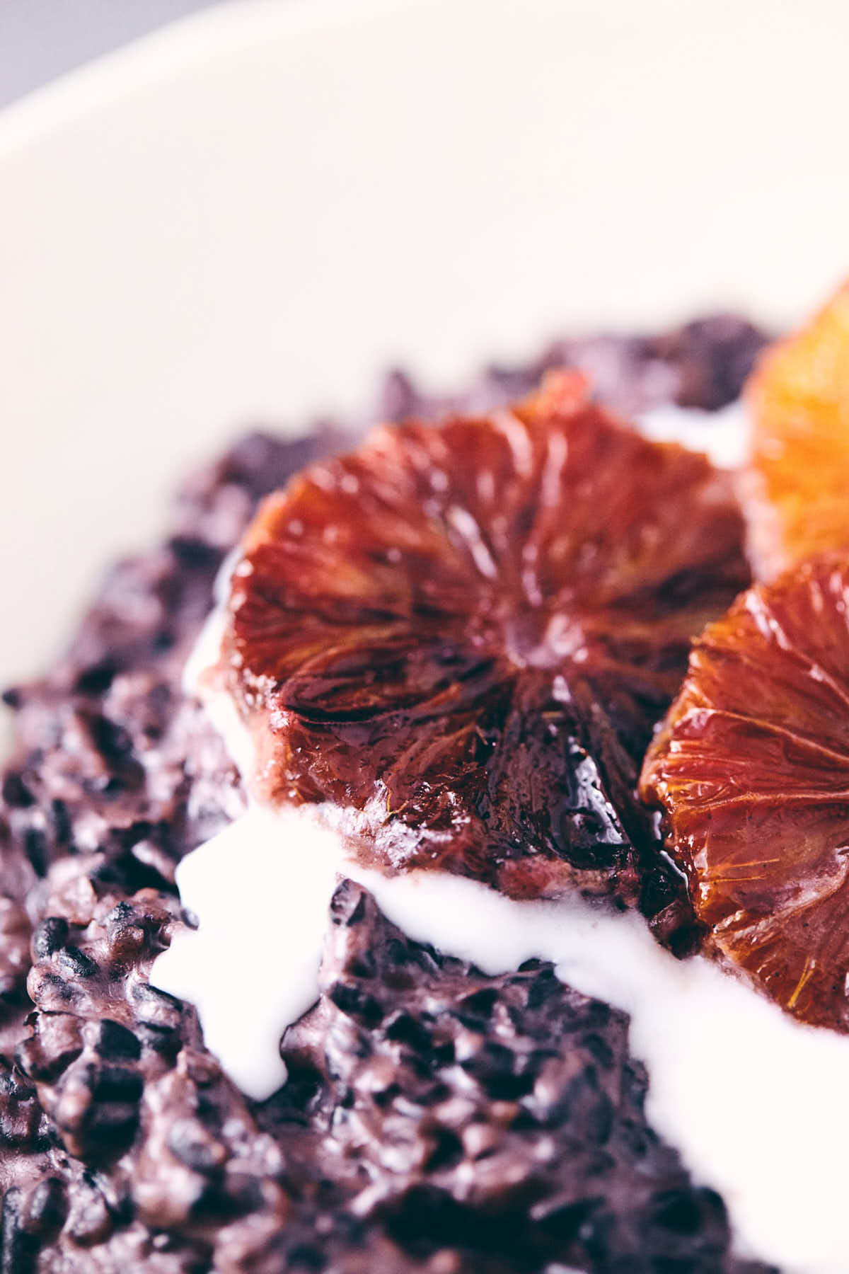 Close up of blood orange on top of black rice pudding and coconut milk