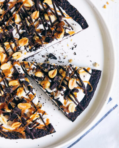 Ice cream pizza topped with peanuts and caramel on a marble counter
