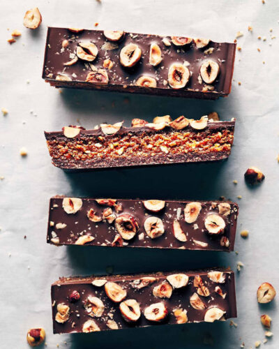 Five chocolate hazelnut praline bars on parchment paper showing both studded top and inside texture