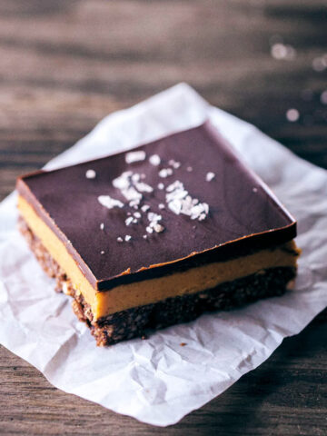 Chocolate peanut butter bars topped with flaky sea salt on white parchment paper