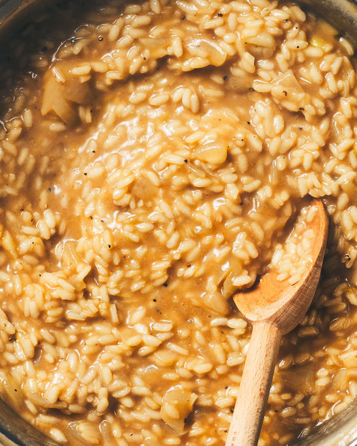 Risotto cooking in a pot with a stirring spoon