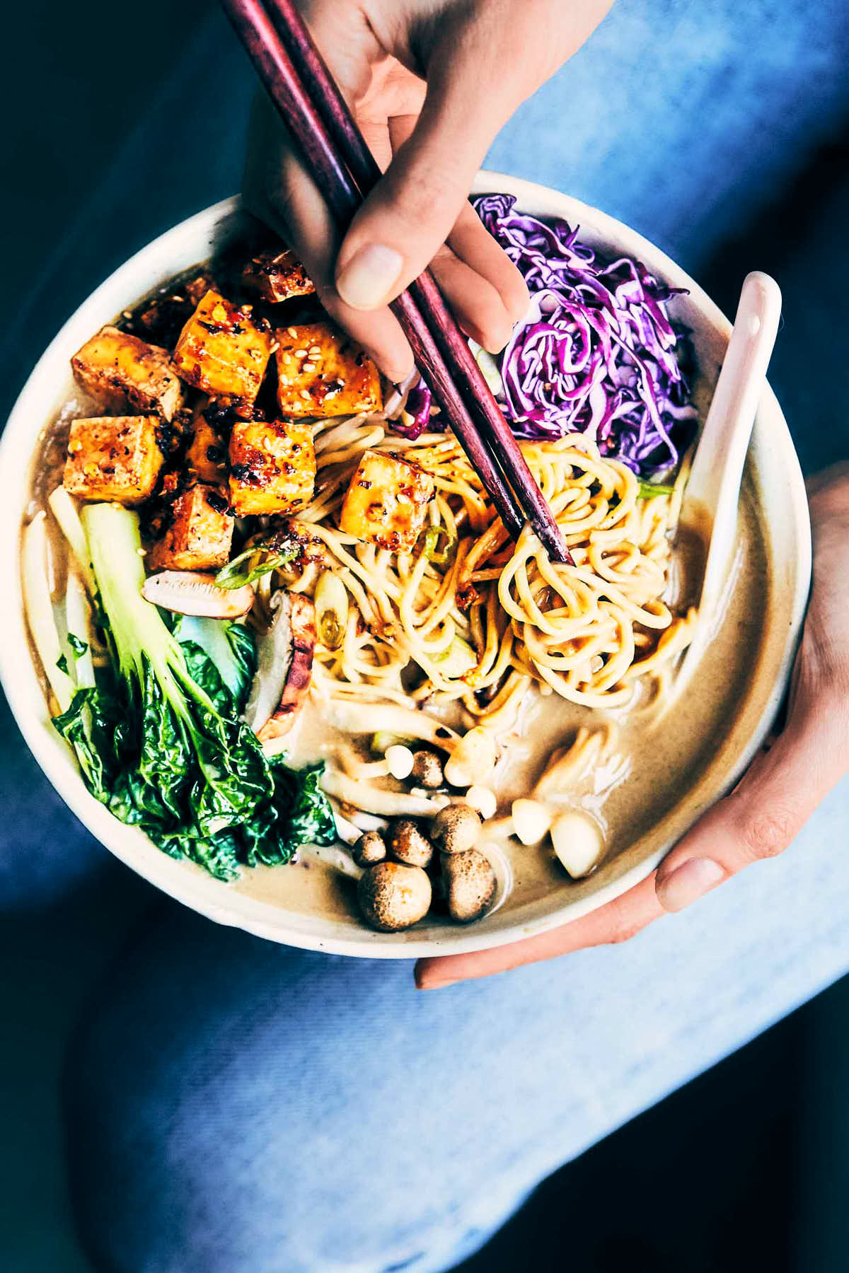 Bowl of creamy vegan ramen with chopsticks digging into ramen noodles