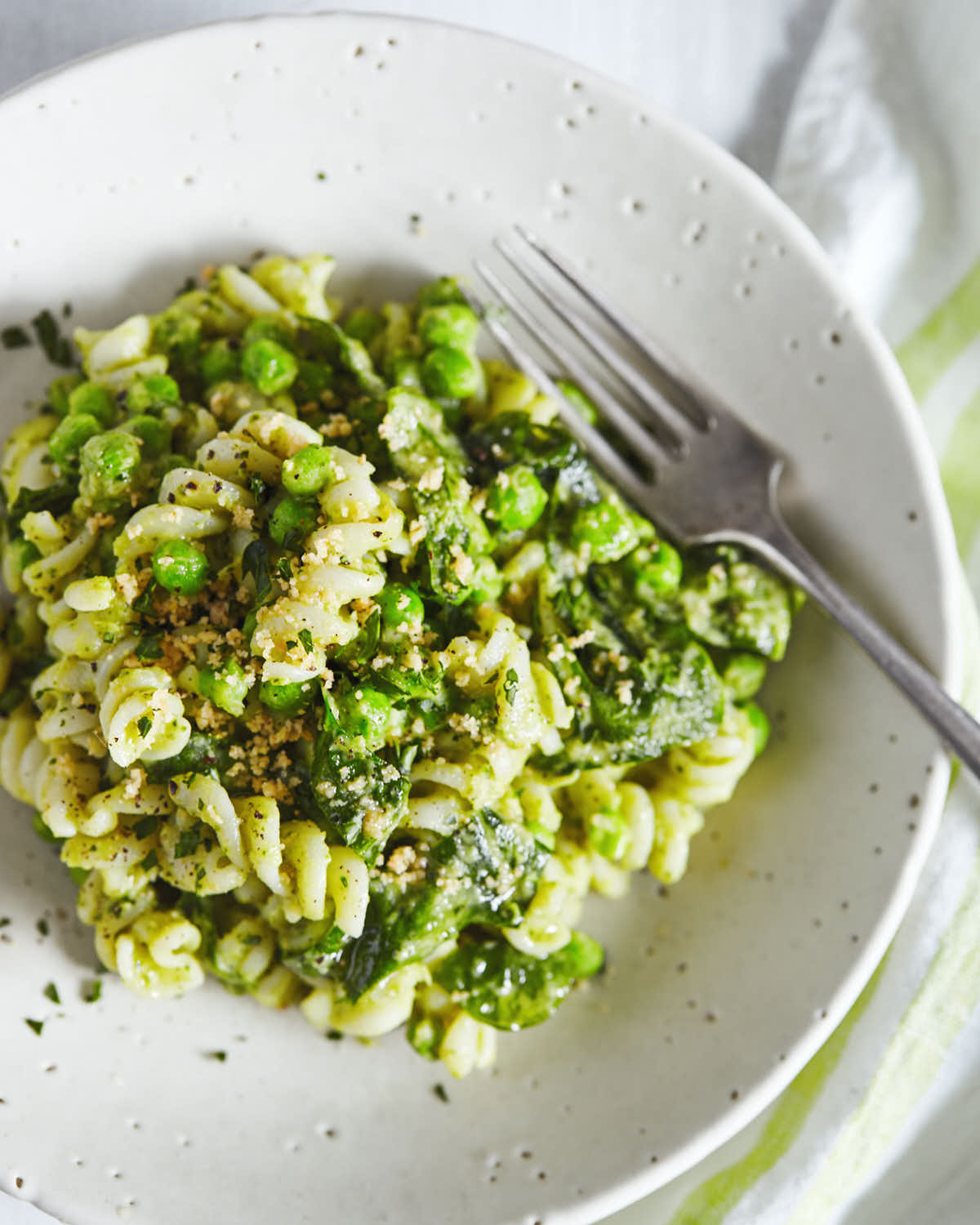 Close up of white bean pesto pasta in a white bowl with fork