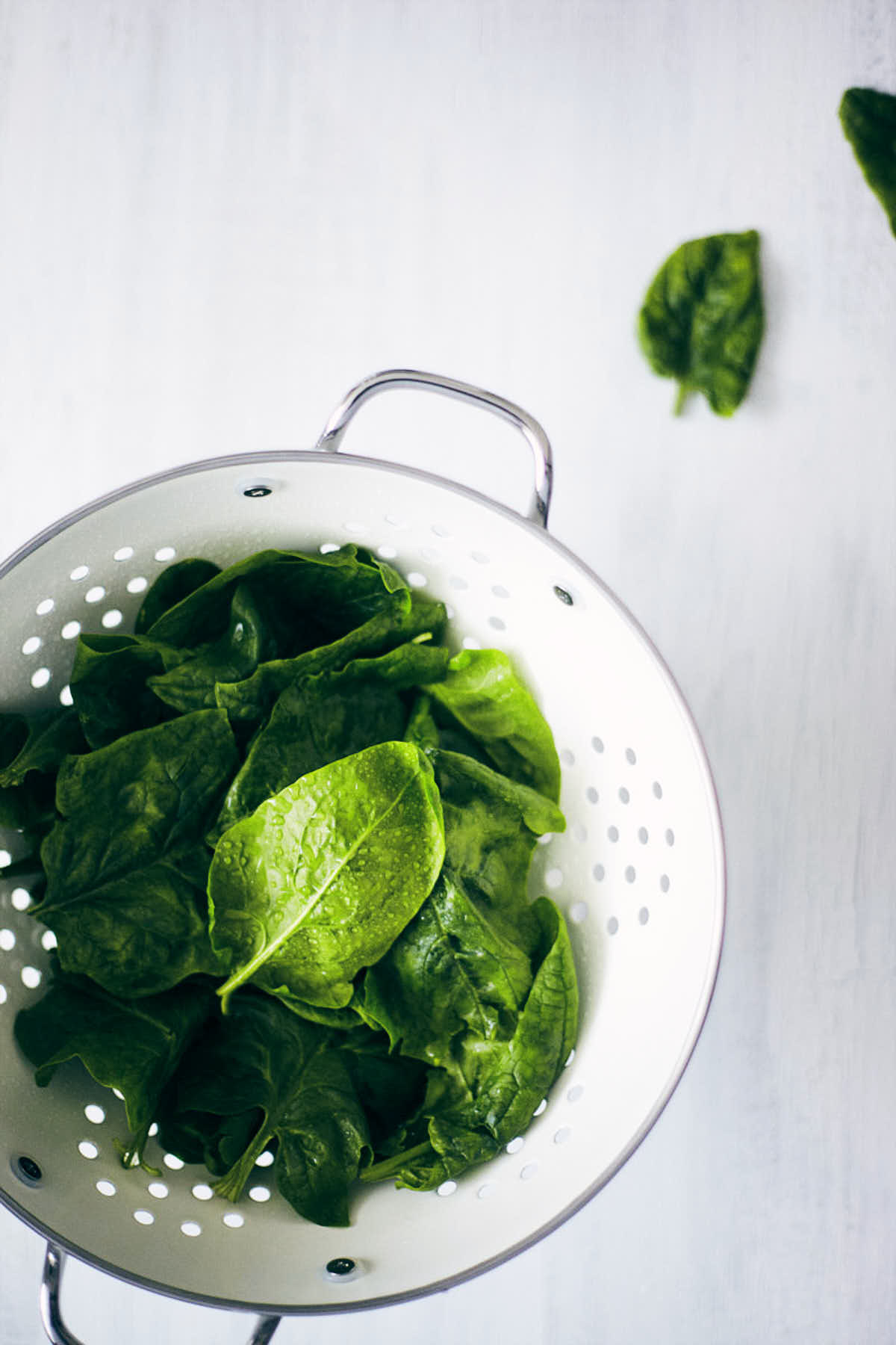 Spinach leaves in a colander after washing