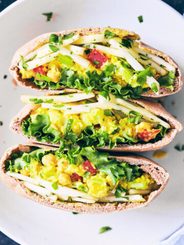 Curry chickpea salad stuffed pitas on a plate with apple slaw