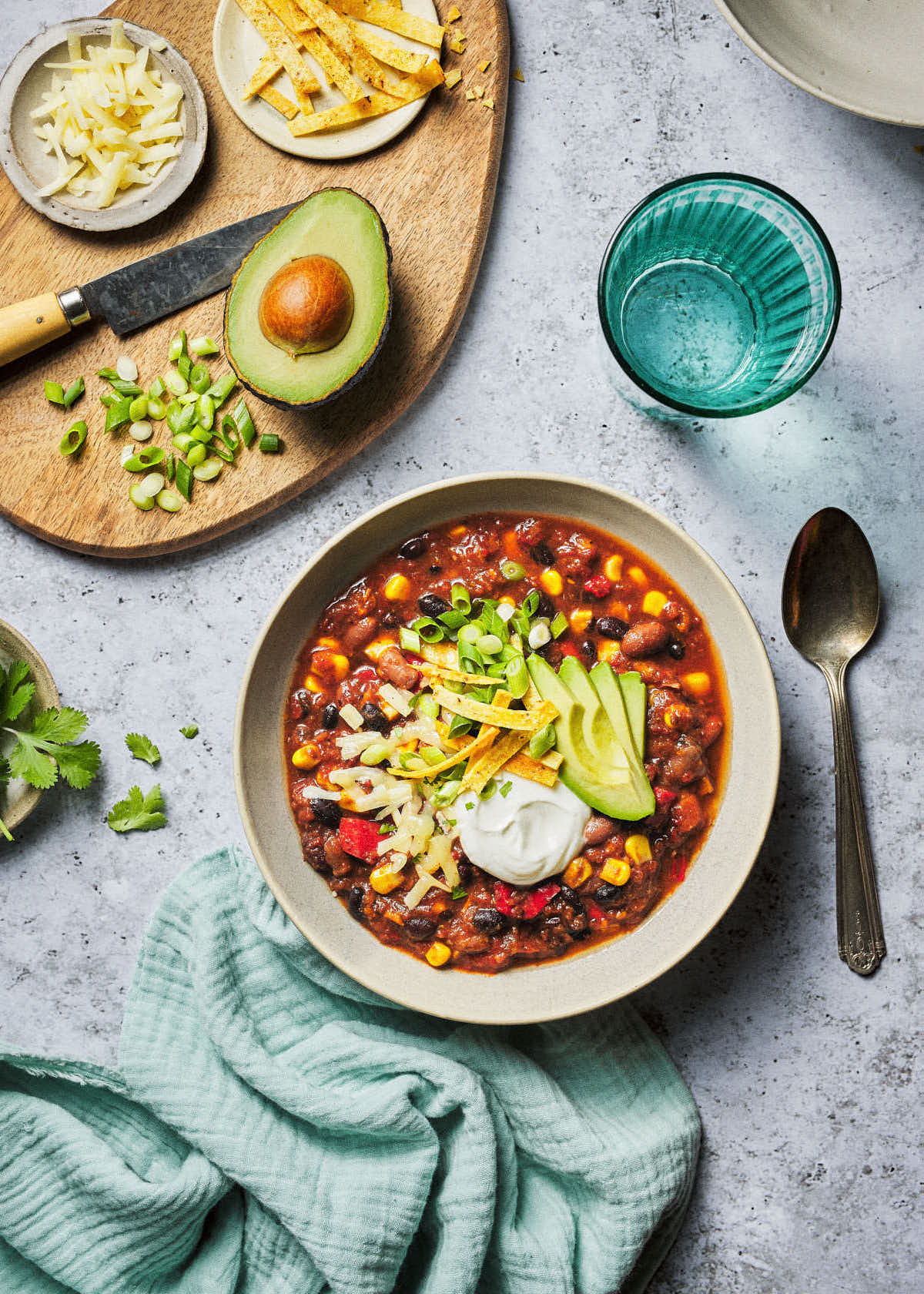 Bowl of veggie chili with toppings on cutting board above