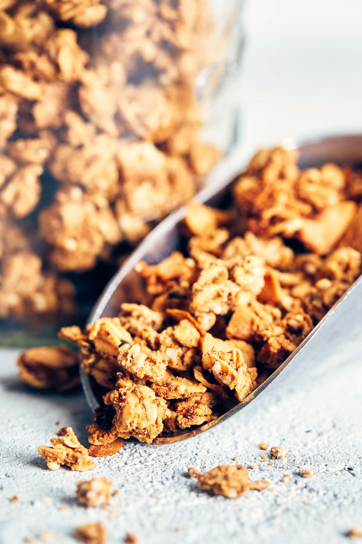 Close up on scoop of nut pulp granola next to a storage jar