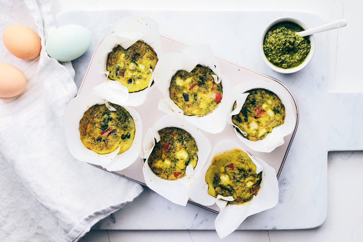Pesto egg muffins cooling on a marble counter