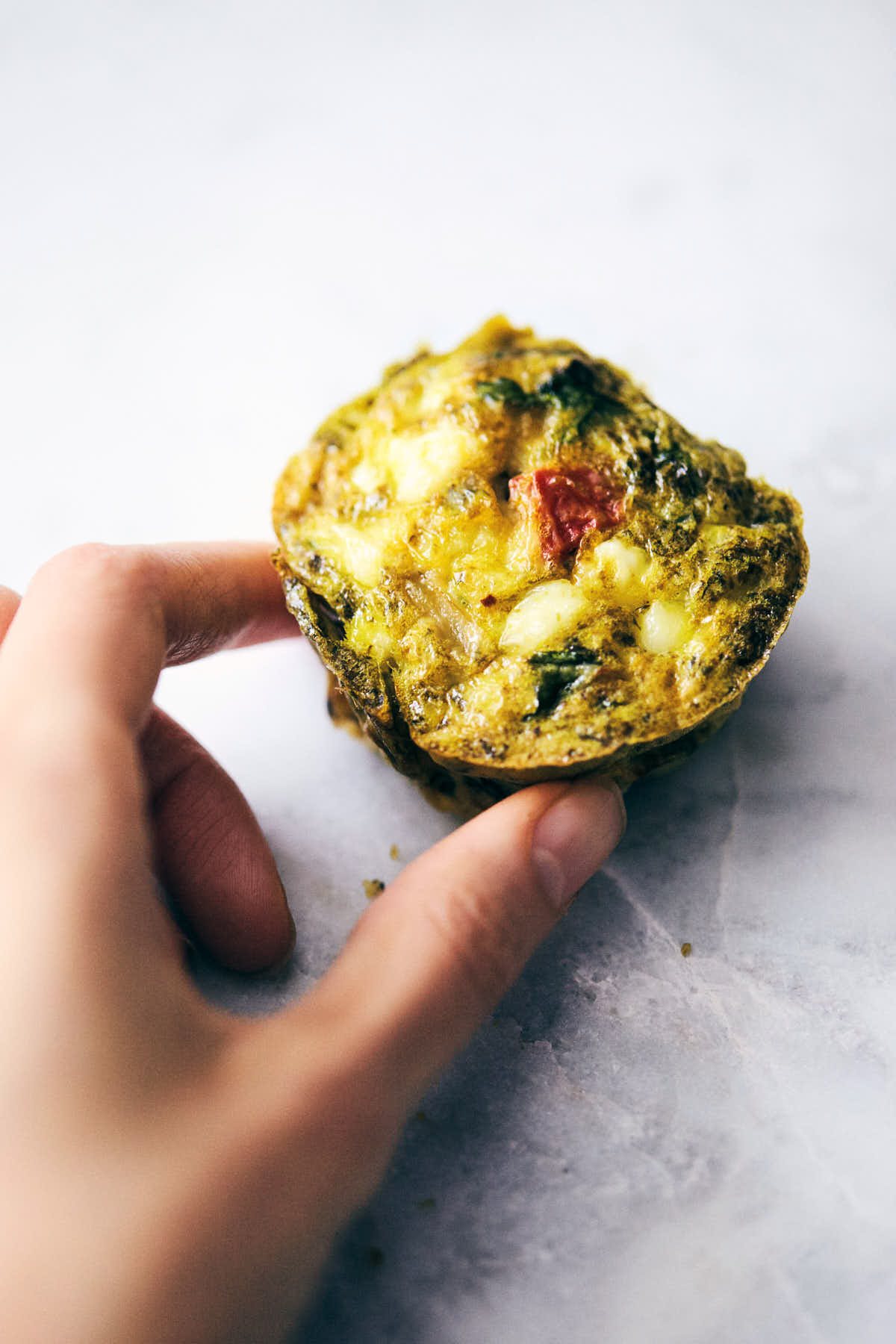 Side view of pesto egg muffins being grabbed by a hand