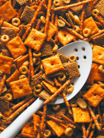 Chex mix cooling in a pan with a white spoon