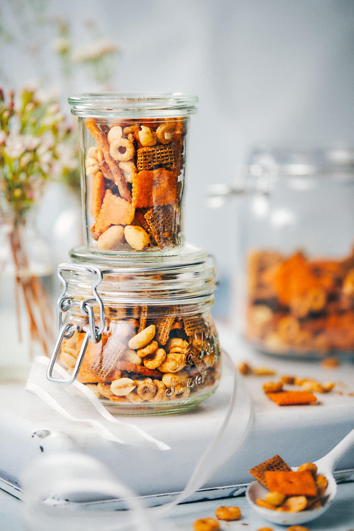 Three jars of chex mix being filled on a counter
