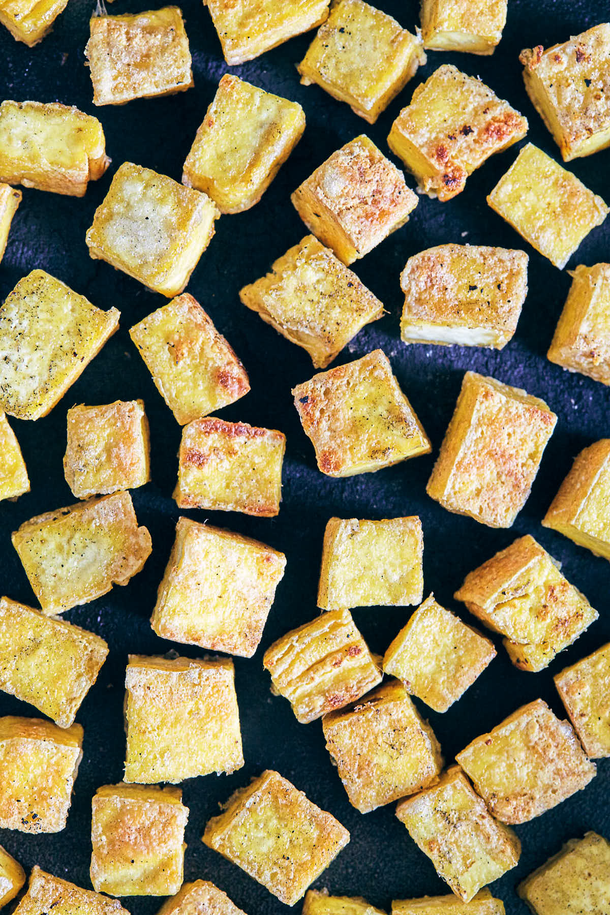 Crispy tofu cooking in a cast iron pan