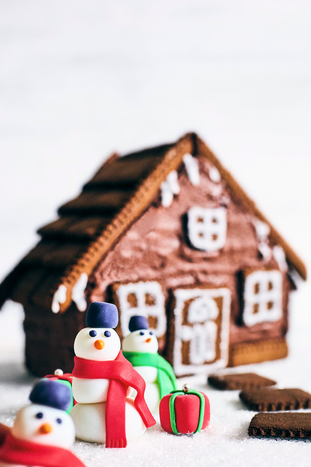 Side view of gingerbread cake house with snowmen in front