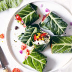 Plate of collard wraps cut in half with veggies inside visible