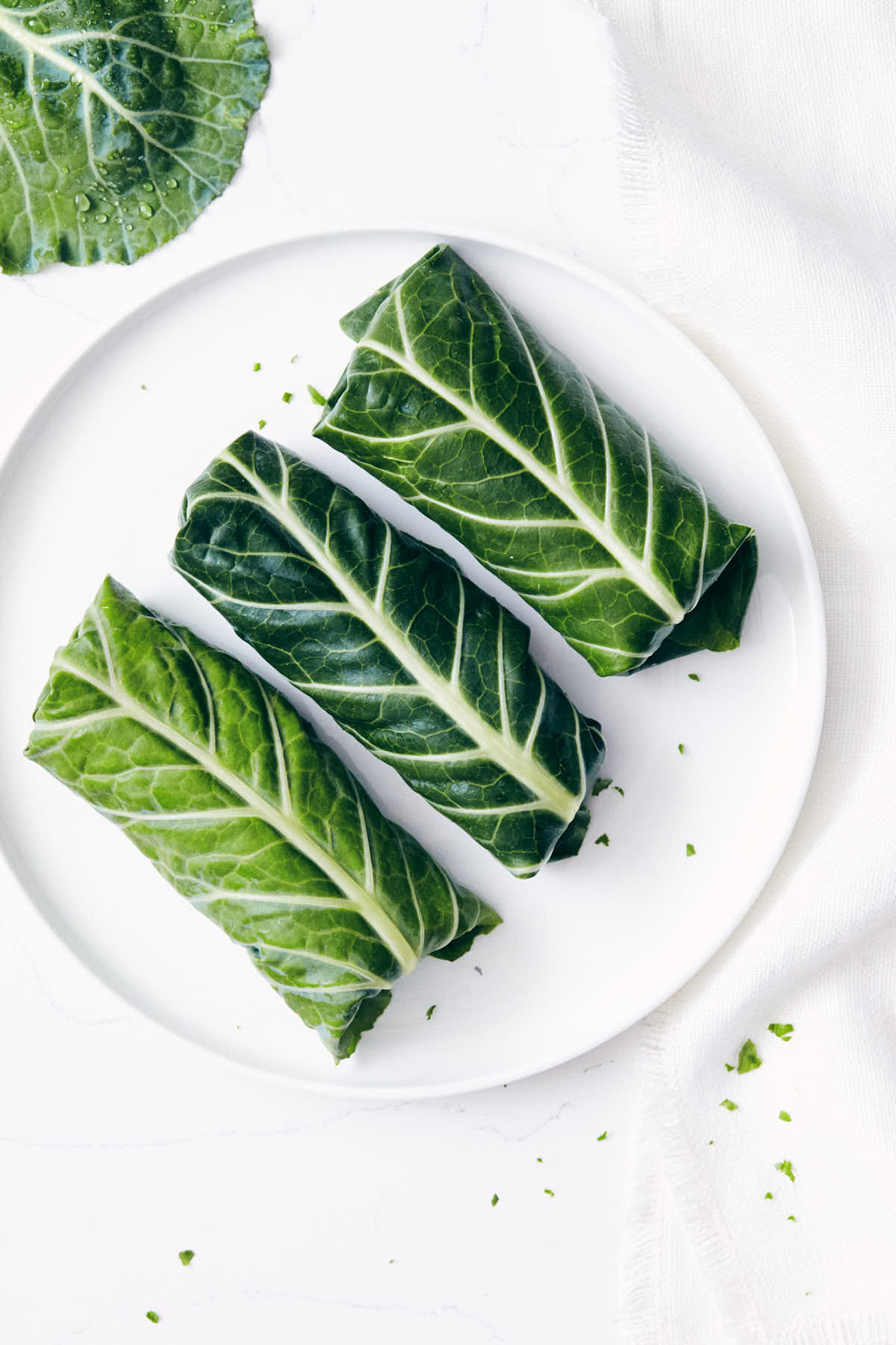 Rolled green collard wraps on a plate pre-cut