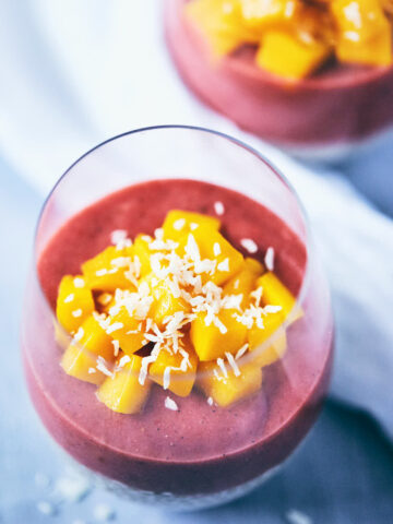 Guava strawberry chia pudding in a glass with chopped mango on top