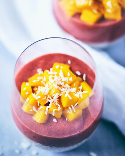 Guava strawberry chia pudding in a glass with chopped mango on top