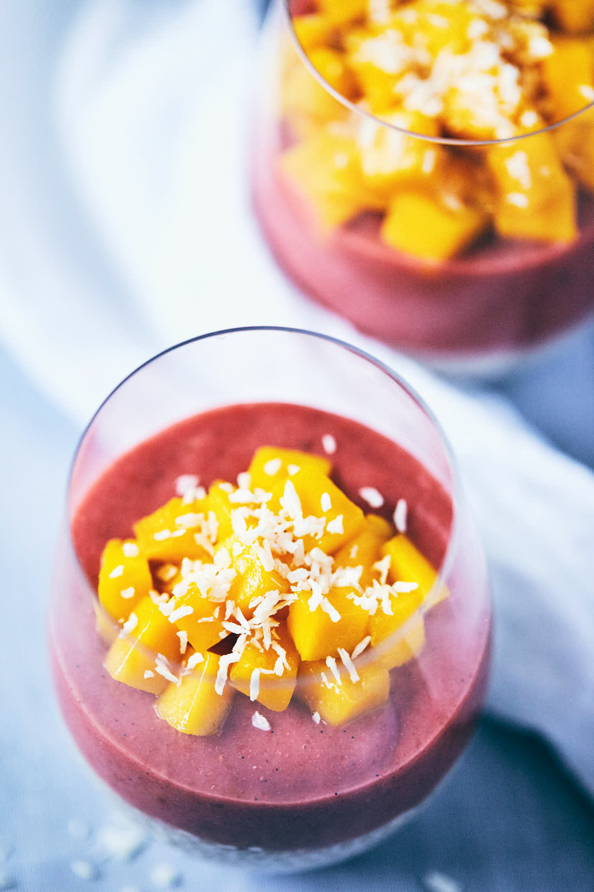 Guava strawberry chia pudding in a glass with chopped mango on top