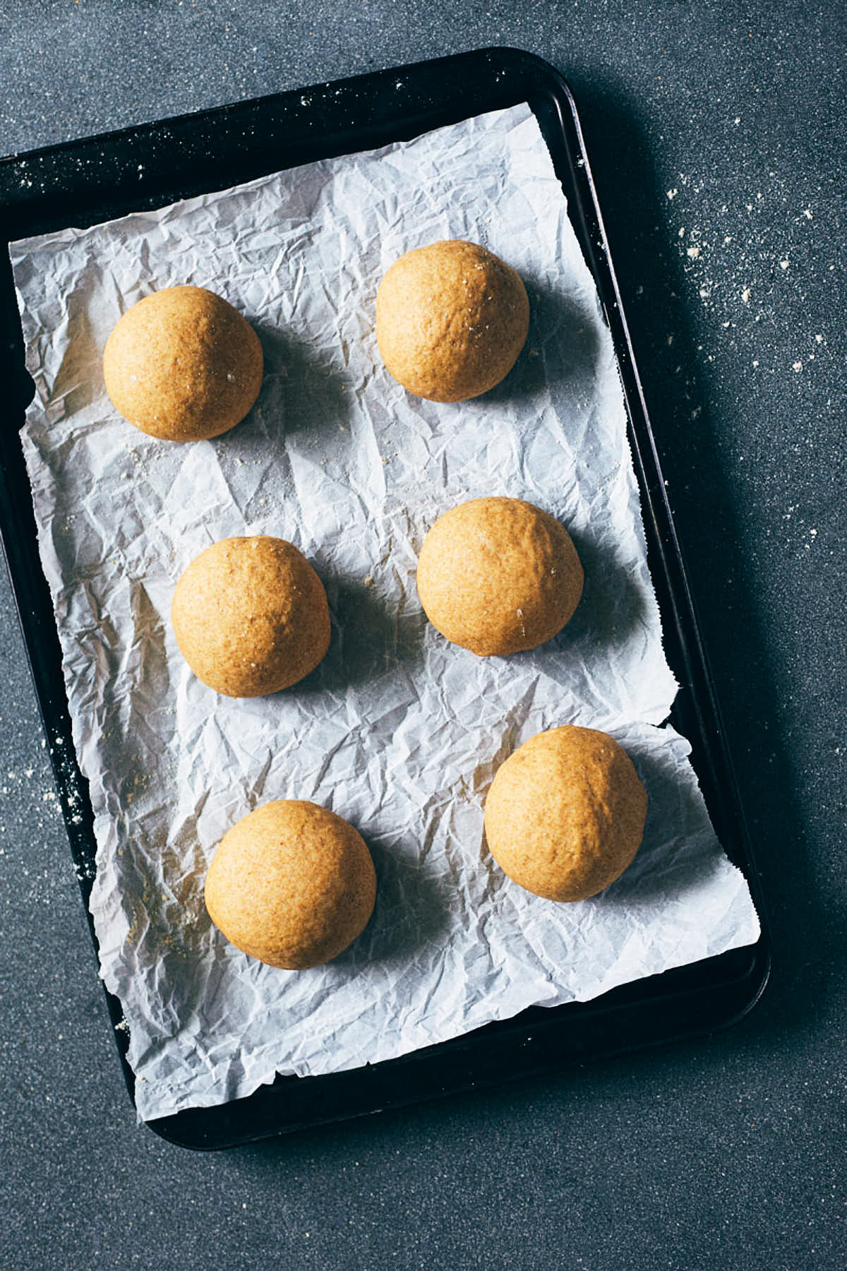 Six pita dough balls on a baking sheet