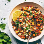 Close up of Mediterranean chickpea casserole topped with parsley, feta and lemon