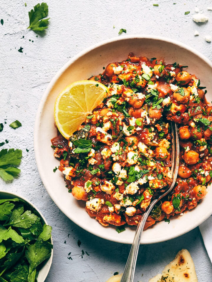Close up of Mediterranean chickpea casserole topped with parsley, feta and lemon