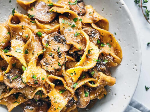 Mushroom Stroganoff in a white plate with fresh thyme and parmesan.