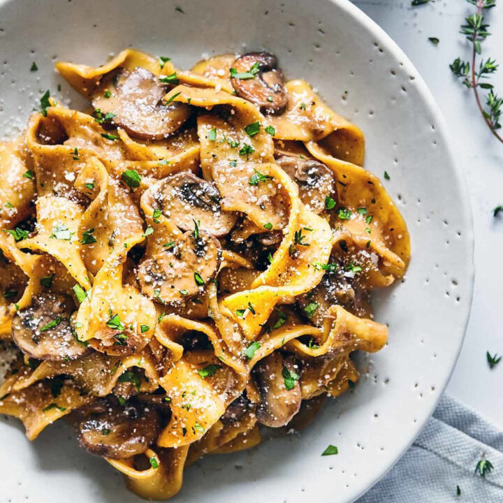 Mushroom Stroganoff in a white plate with fresh thyme and parmesan.