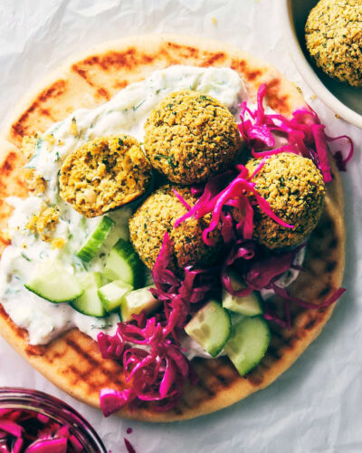 Close up of falafel on a pita with pickled cabbage and tzatziki