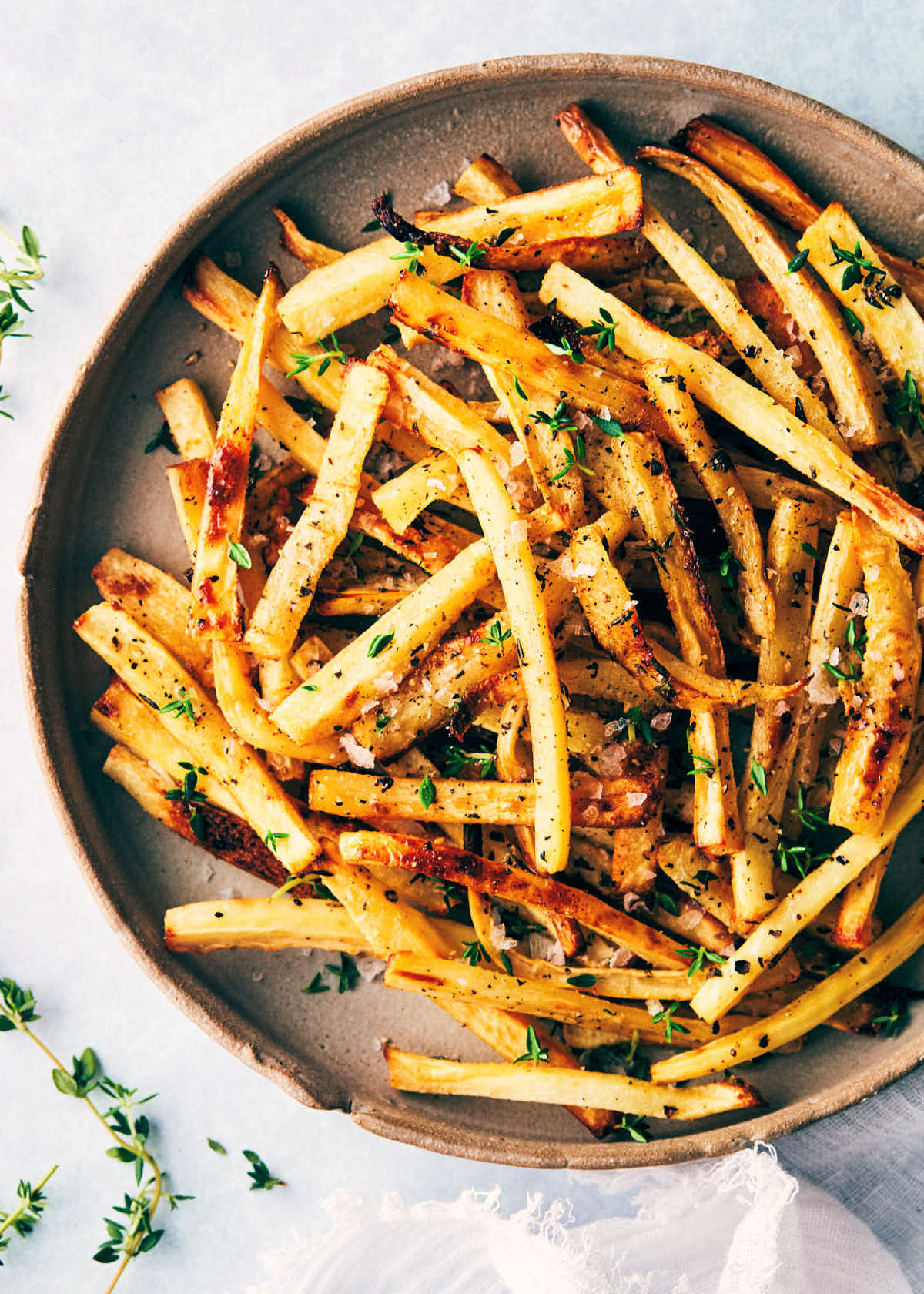 Plate of parsnip shoestring fries topped with thyme and flaky salt