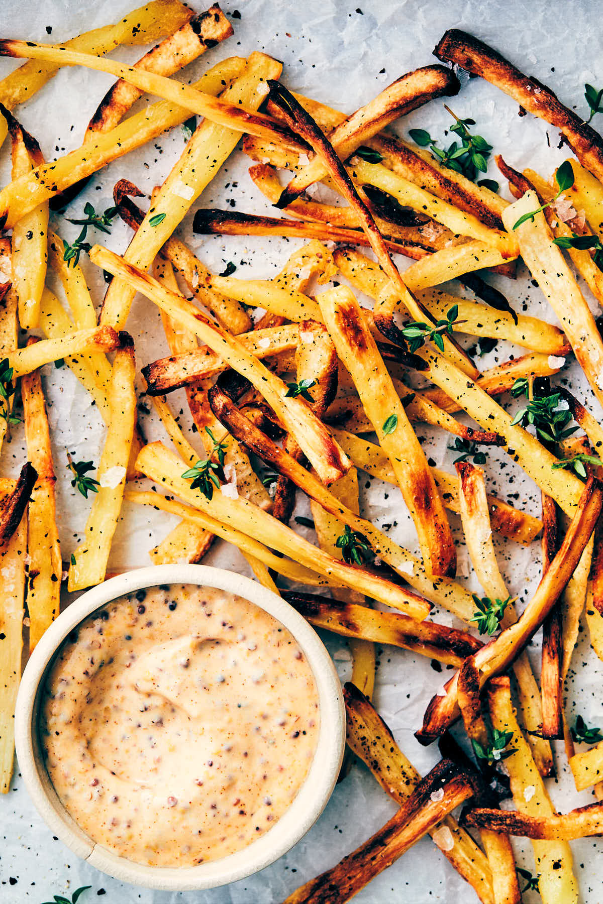 Baking sheet of parsnip fries fresh out of the oven with easy vegan dijon aioli