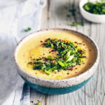 Side view of potato parsnip and leek soup with chive gremolata on a wooden surface