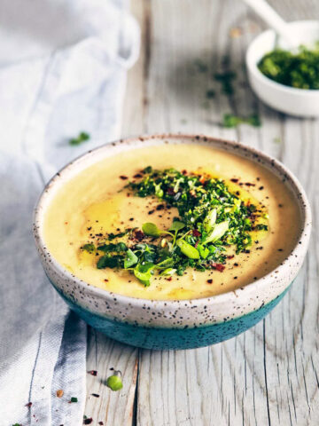 Side view of potato parsnip and leek soup with chive gremolata on a wooden surface