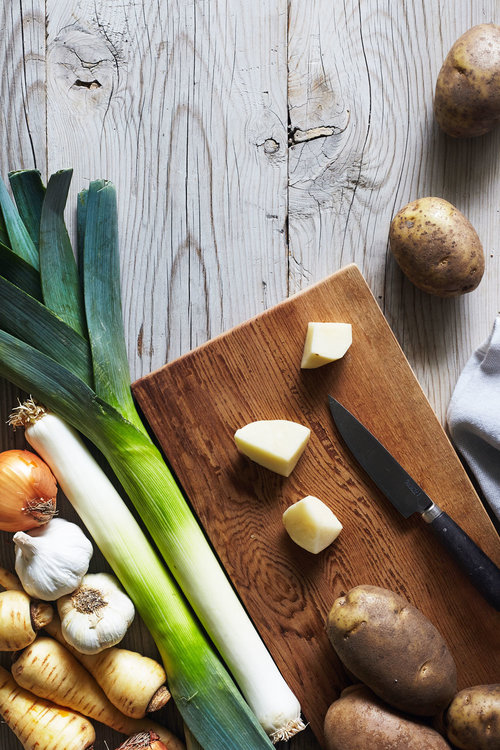 Cutting board with leeks, garlic and potatoes before cooking
