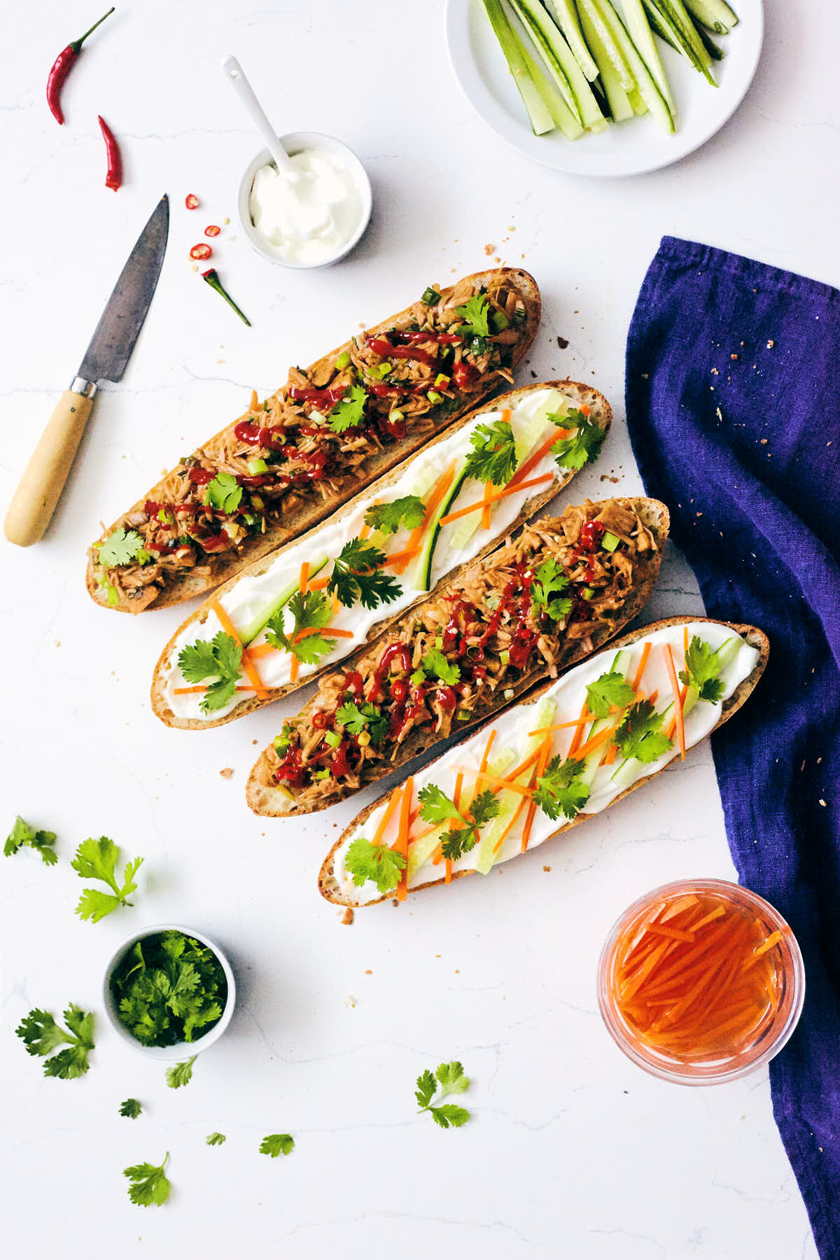 Two open-faced pulled jackfruit banh mi sandwiches on a marble counter ready to be enjoyed