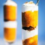 Two pumpkin pie parfaits with a blue background