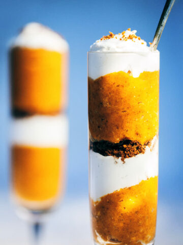 Two pumpkin pie parfaits with a blue background