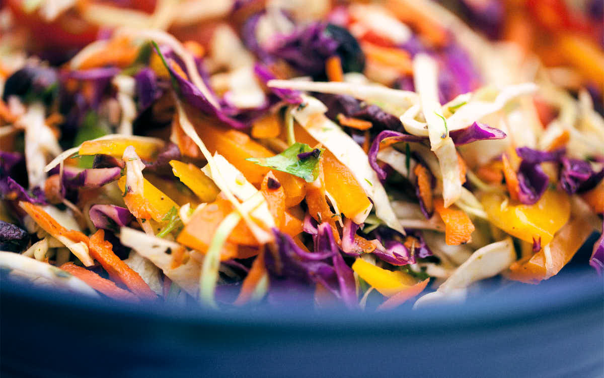 Side view of rainbow slaw in a blue bowl