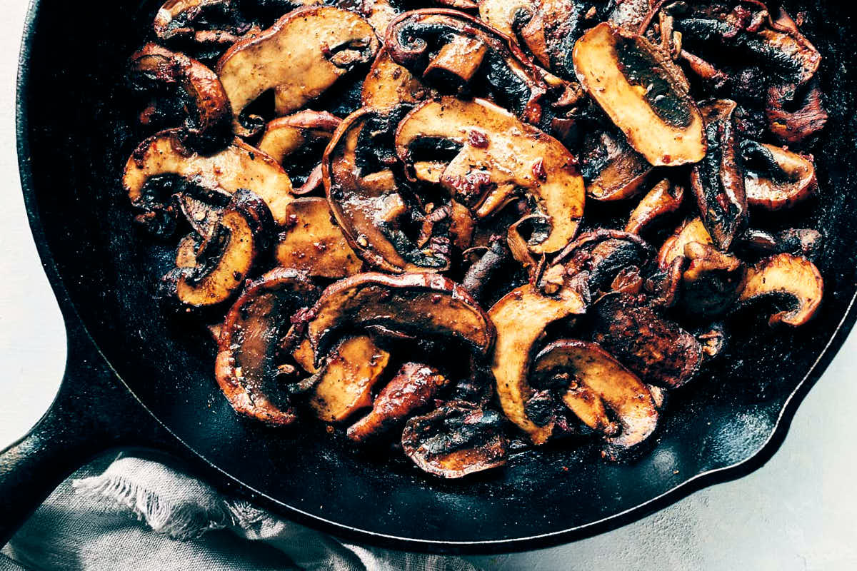 Portobello mushrooms being cooked down in a cast iron pan