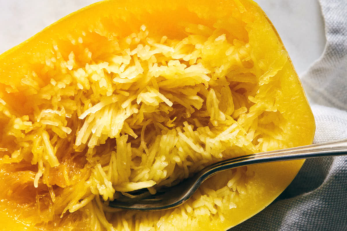 Raking cooked spaghetti squash with fork to create noodles
