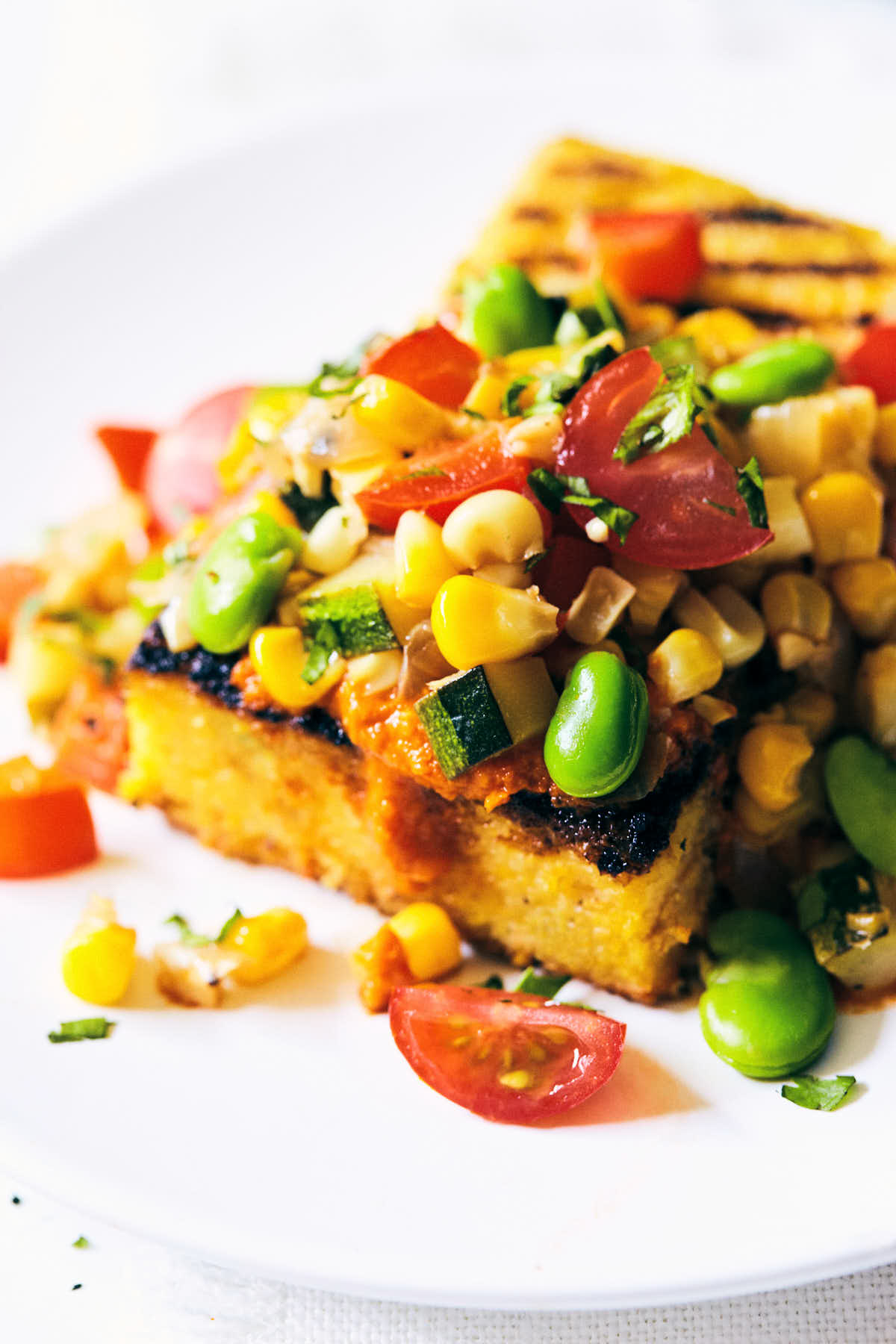 Side view of summer succotash on a plate with grilled polenta