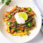Vegan chili fries on a white table with fork ready to dig in