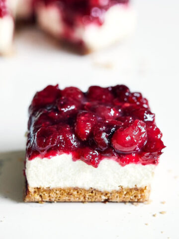 Side view of vegan cranberry cheesecake bar on a marble surface