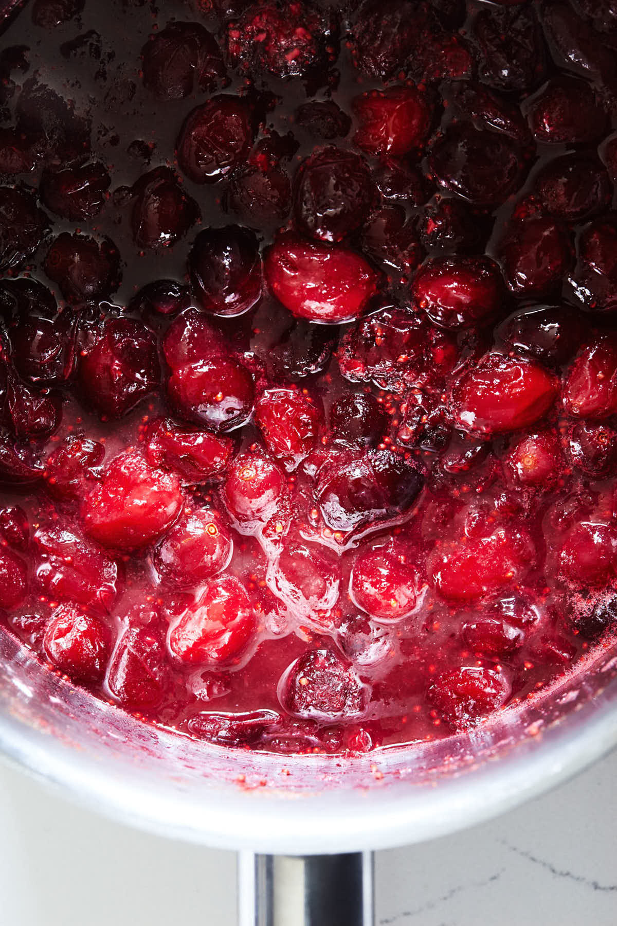 Cranberries cooking down in a small saucepan