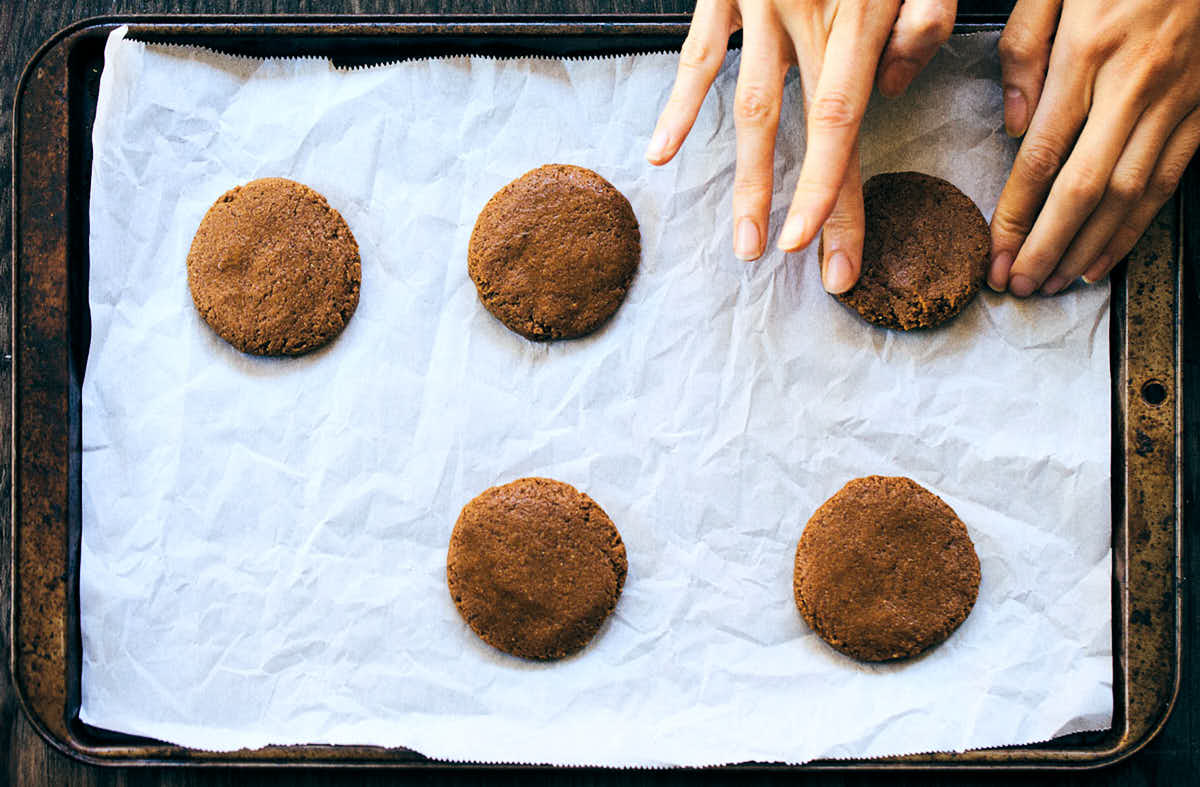 Placing ginger molasses cookies on a baking tray and shaping them using hands