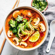 Bowl of vegan tom yum soup topped with fresh cilantro and lime