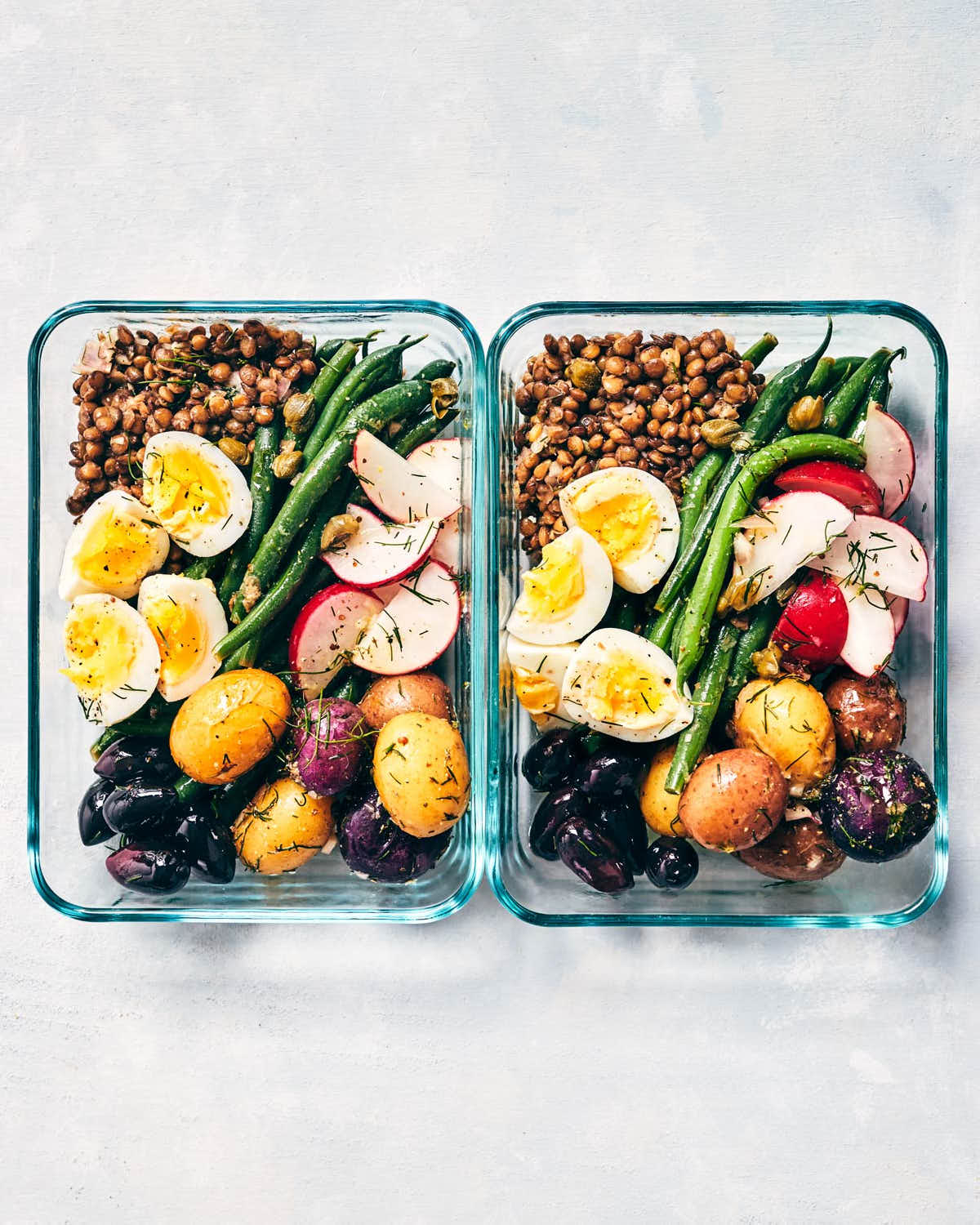 Two pyrex containers of nicoise salad ready to packed away for a meal prepped lunch
